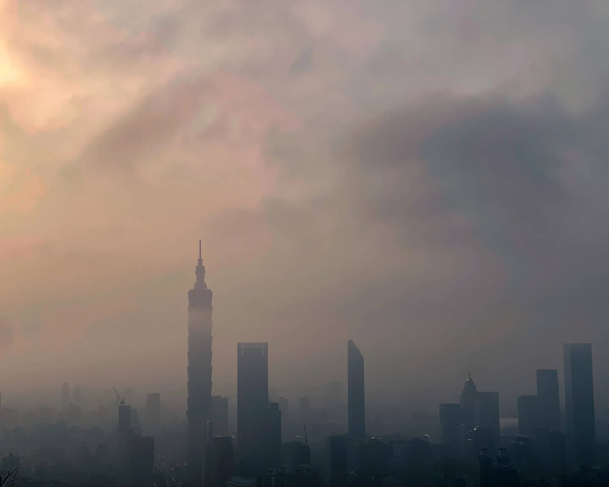 Taipei 101 rising out of a hazy grey skyline, the rest of the city dissolving into low cloud behind it.